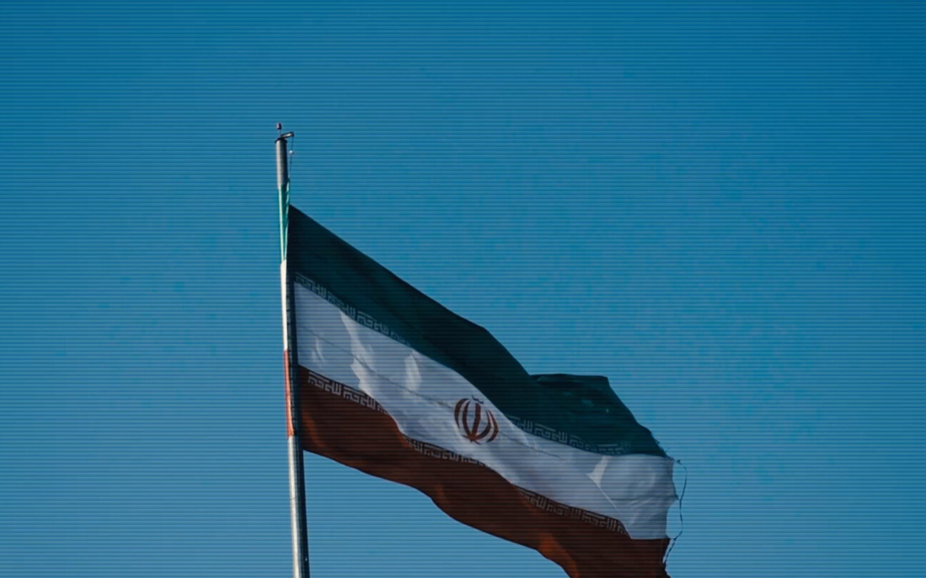 Screenshot from the trailer for Alamut by Laibach. The picture depicts an Iranian flag blowing in the wind.