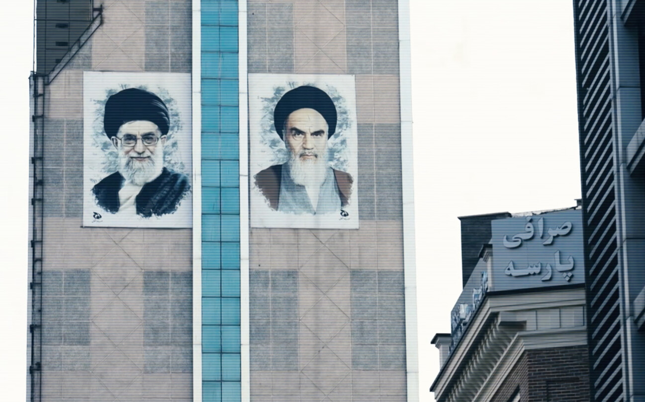 Screenshot from the trailer for Alamut by Laibach. The picture depicts a building featuring two images of Iranian politicians on the side.